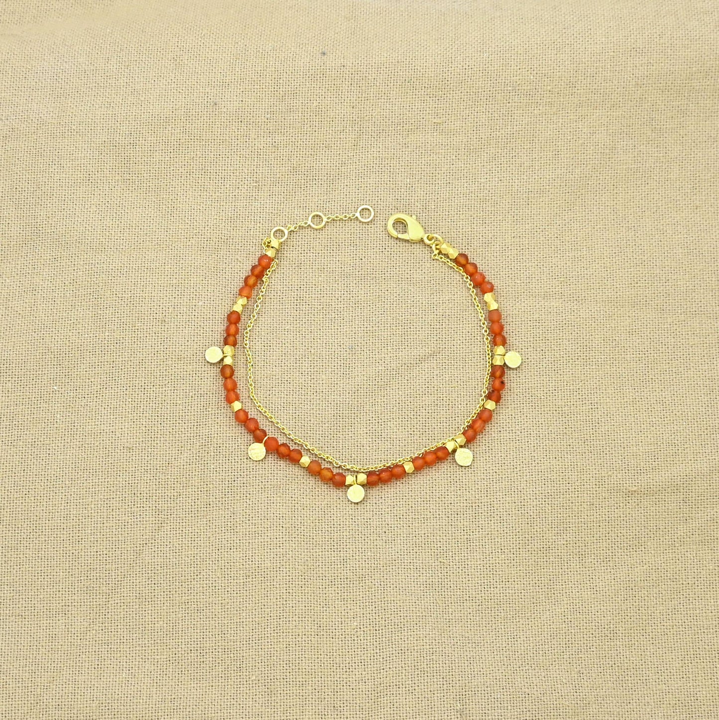 Pulsera dorada de cornalina con cadena fina y dijes.