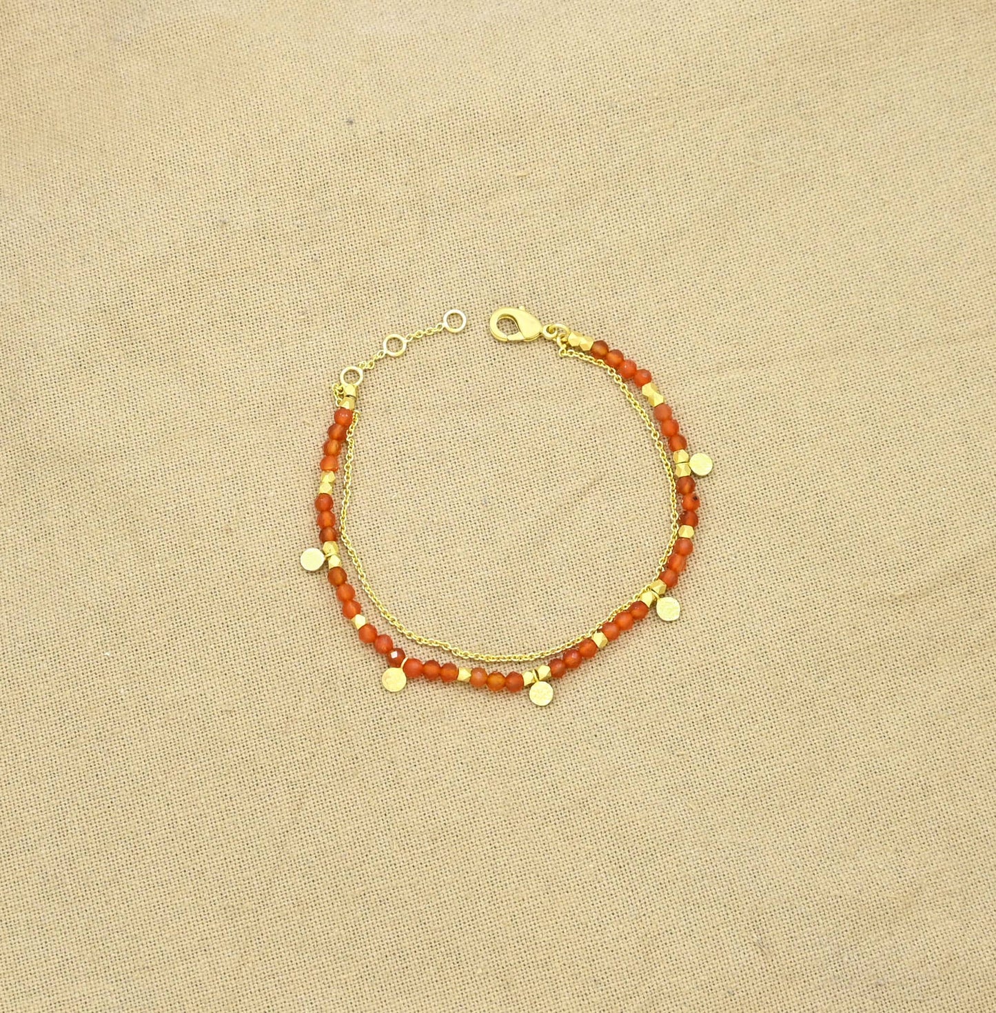 Pulsera dorada de cornalina con cadena fina y dijes.